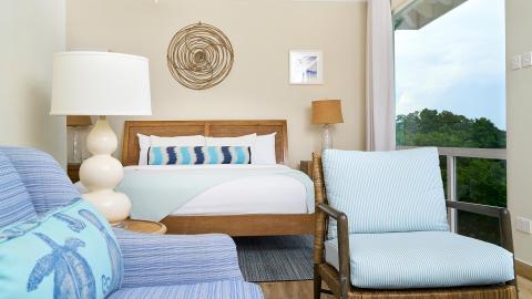 Coastal themed bedroom with blue striped duvet and wooden headboard, natural view.