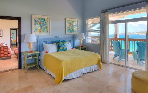 Ocean view bedroom with vibrant yellow bedspread and balcony seating
