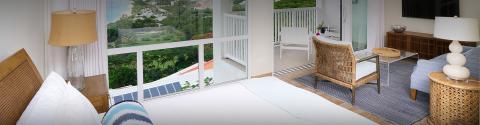 Serene bedroom with balcony overlooks lush landscape, modern cozy decor.