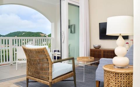 Elegant room with rattan chair leading to balcony overlooking scenic hills