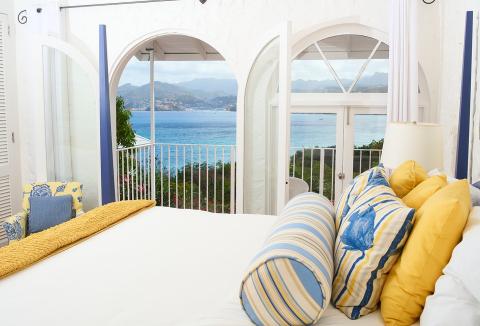 Coastal bedroom with sea view, blue and yellow decor, balcony plants