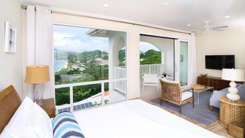Stylish bedroom with a sea view, balcony, large bed, and modern decor in a luxury retreat.