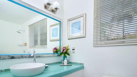 Modern bathroom with turquoise tiles, vessel sink, and ocean-themed decor.
