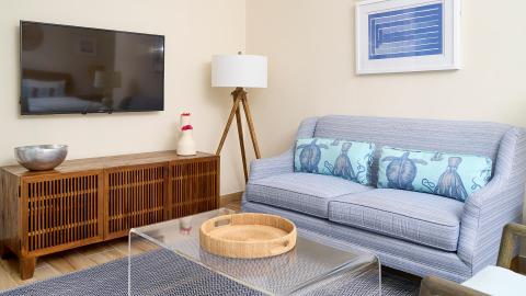 Contemporary living room with blue-striped sofa, abstract art, and flat-screen TV.