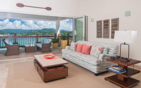 Spacious living room with balcony view, tropical decor, and cozy furniture