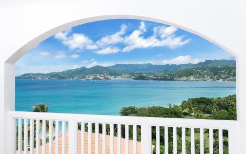 Tropical seascape with turquoise sea and lush coastline viewed from arched window.