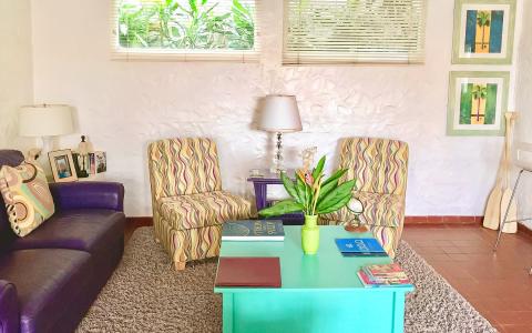Eclectic living room with colorful striped armchairs and tropical decor.