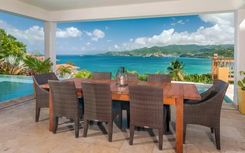 Coastal outdoor dining area with infinity pool and bay view