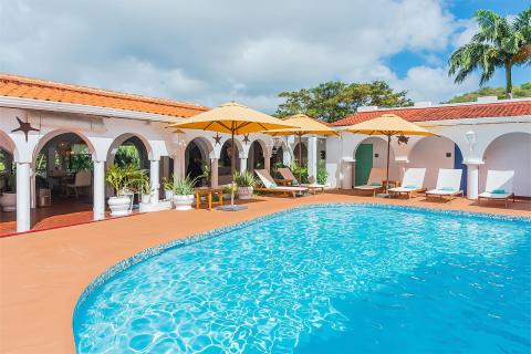 Sunny pool area with blue water, white loungers and yellow umbrellas at luxury resort