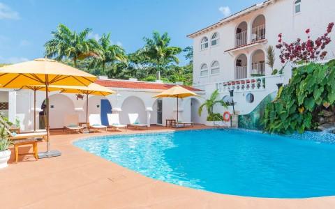 Luxurious kidney-shaped pool at a Mediterranean villa with yellow umbrellas.