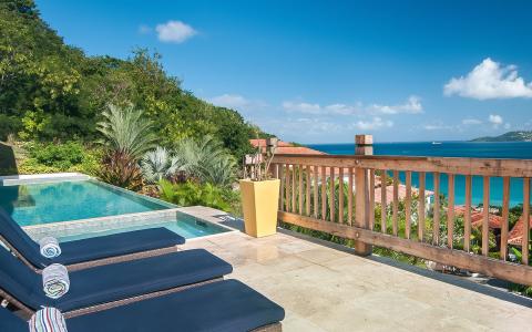 Luxury pool with blue loungers, coastal view, yellow planter, inviting tropical ambiance.