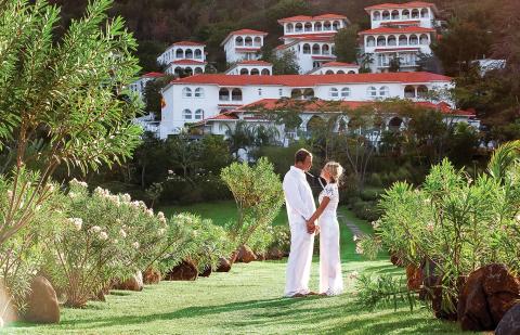 Romantic couple in white at garden wedding with hillside resort backdrop