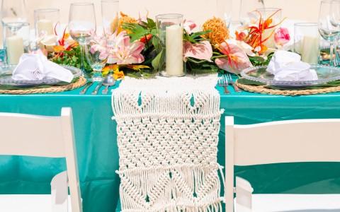 Elegant wedding table setting with turquoise linen and vibrant floral centerpiece