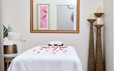 Romantic spa room with rose petals on bed and candles for serene ambiance.
