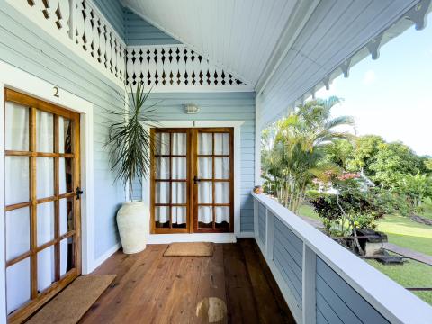 Light blue porch with white trim, wooden floors, and garden view on a sunny day