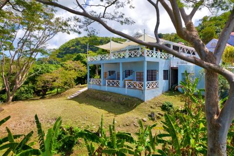 Charming two-story blue house with white railings in a tropical setting