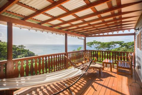 Serene patio with ocean view, hammock, and wooden furnishings.