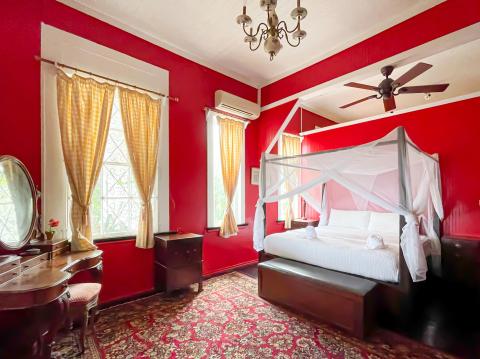 Opulent red bedroom with four-poster bed, gold curtains, and classic furniture.