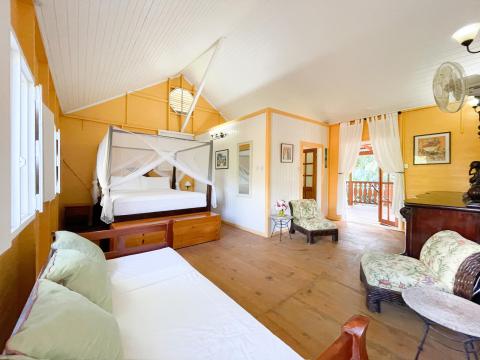 Spacious tropical bedroom with four-poster bed and yellow walls