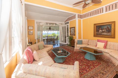 Sunny living room with sofa, glass coffee table, and outdoor dining view.