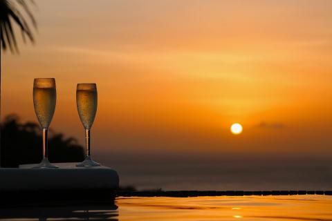 Romantic sunset with champagne by infinity pool, reflecting serene hues