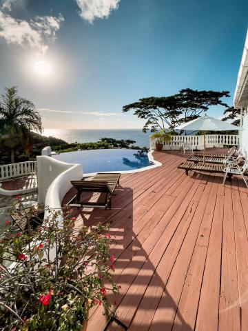 Luxury infinity pool with sea view, loungers, and shaded seating area