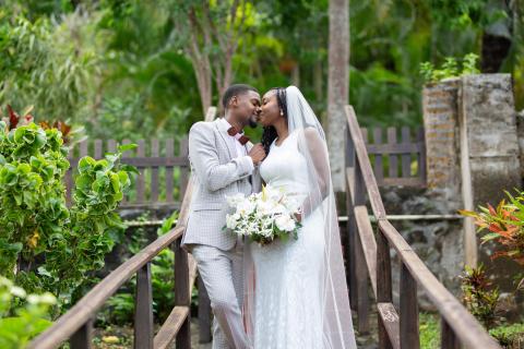 Bride and groom kissing on bridge in garden wedding scene