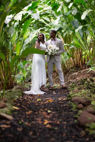 Bride and groom walking on a pebble path in a tropical forest at their wedding