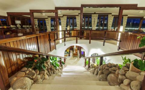 Luxurious interior with curved staircase, wooden railings, and lush plants