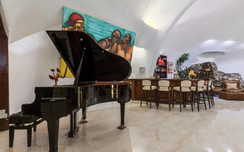 Modern interior with grand piano, bar, and cozy fireplace setup.