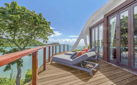 Modern house deck with sea view, stylish lounge, and lush greenery