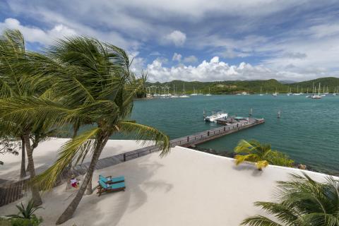 Tropical beach scene with palm trees, lounge chairs, pier, and sailboats