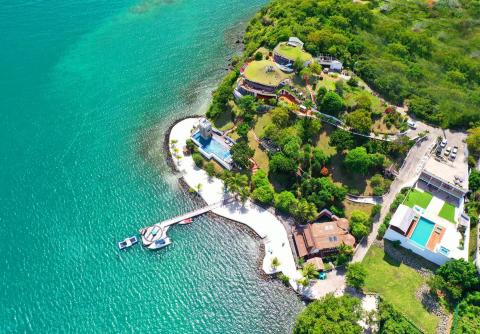 Aerial view of a lush green peninsula with colorful buildings and turquoise waters