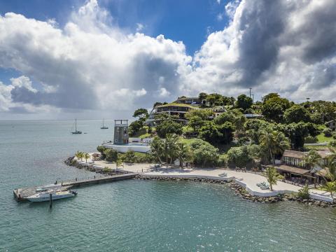 Scenic coastal view with pier, beach chairs, boats, and diverse architecture.