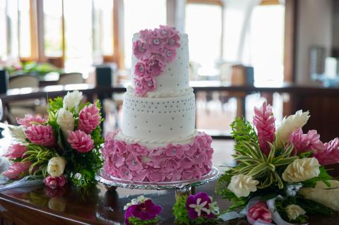Exquisite three-tiered floral cake on elegant stand at a bright venue.