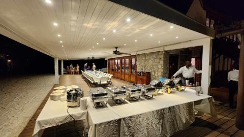 Outdoor night buffet dining setup at beach venue with guests and servers.