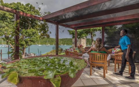 Outdoor dining by harbor with boats, pergola-covered table, and water lilies.