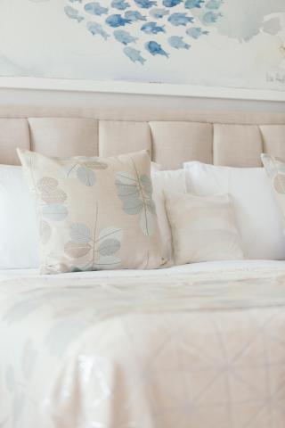 Stylish bedroom with pastel leafy quilt and blue fish artwork above bed