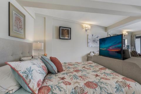 Stylish bedroom with sea-themed decor, modern TV, and cozy gray sofa.