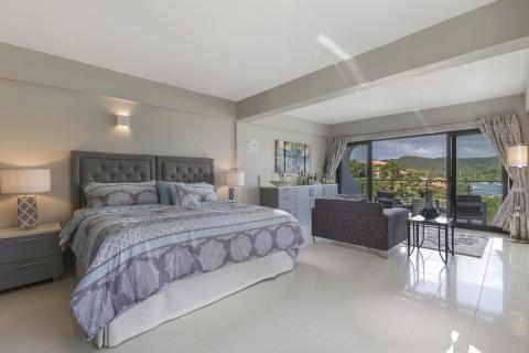 Modern bedroom with scenic view, double bed, and elegant grey-white decor.