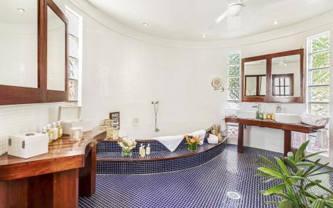 Luxurious circular bathroom with white mosaic tiles and dark blue accents.