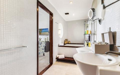 Luxurious bathroom with wood-paneled bathtub, modern sink, and bright tiled floor.