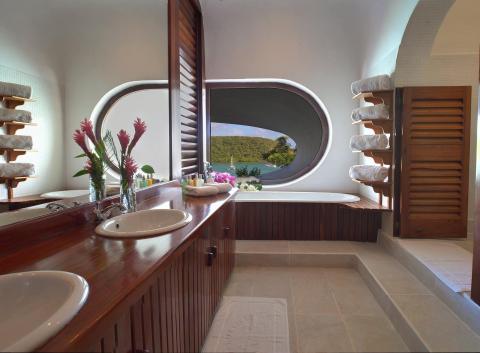 Luxurious bathroom with dual sinks, wooden vanity, and oval window view.