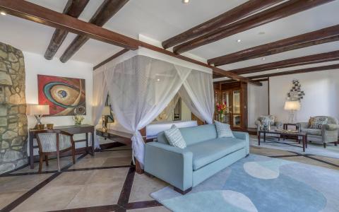 Luxurious bedroom with wooden beams, four-poster bed, and elegant decor.