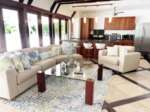 Contemporary living room with beige sofa, decorative rug, and modern kitchen background.