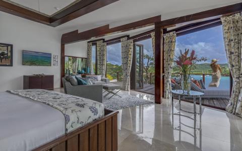 Luxurious bedroom with outdoor deck overlooking a scenic lakeshore.