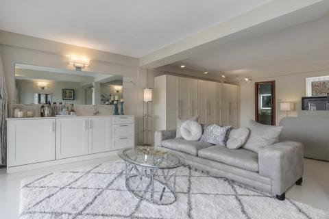 Modern living room with plush sofa, glass coffee table, and built-in mini bar area.