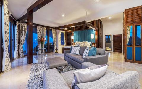 Modern elegant living room with gray sofa set, wooden beams, and large windows.