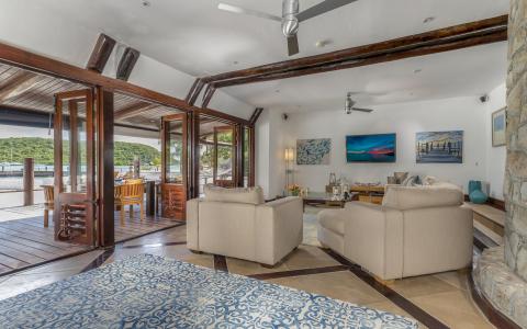 Rustic luxury living room with wooden beams, cream couches, and marina views