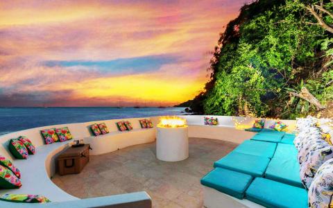 Luxurious seaside outdoor seating area at sunset with fire pit and ocean view